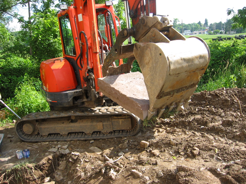 0052--L3 grappled with excavator bucket and "thumb" to its site.
