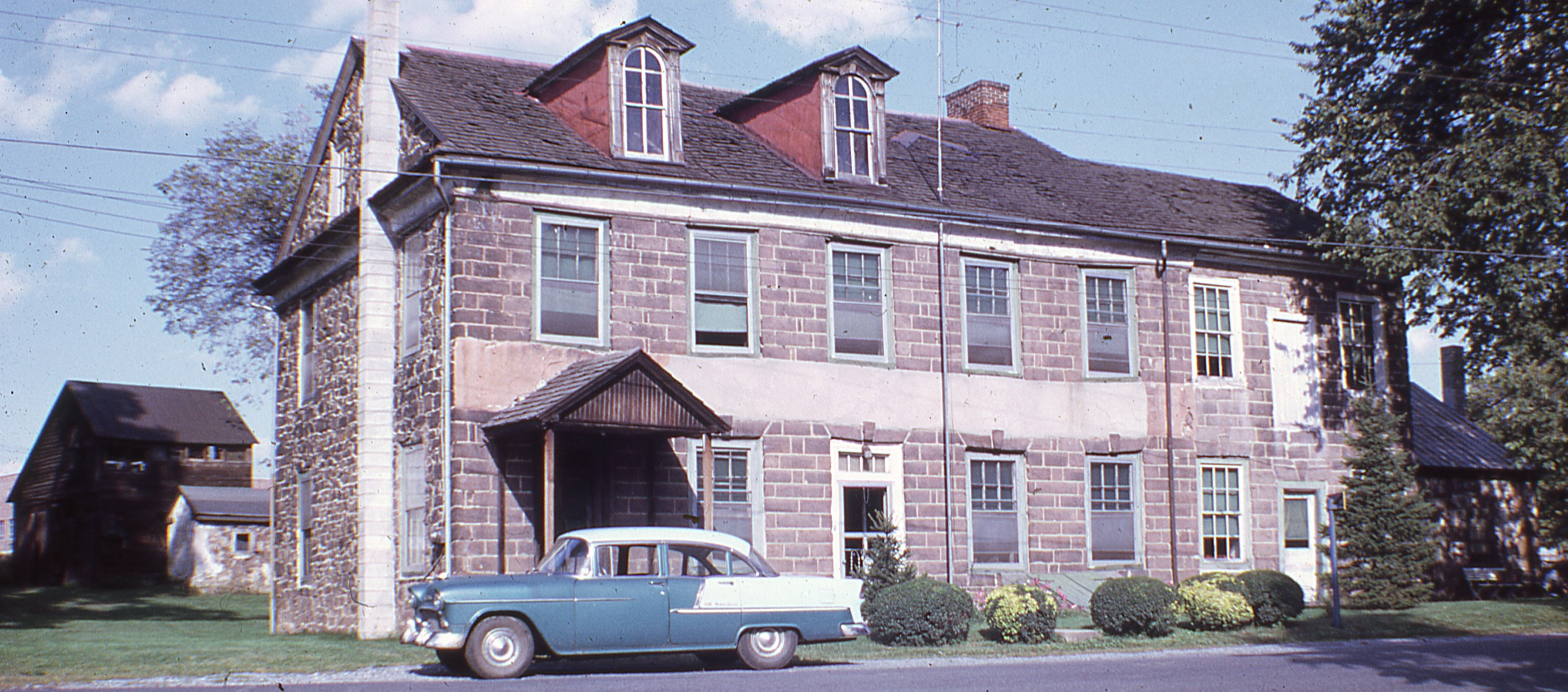 1950s photo showing 2 surviving dormers, frame barn, small stone buildings